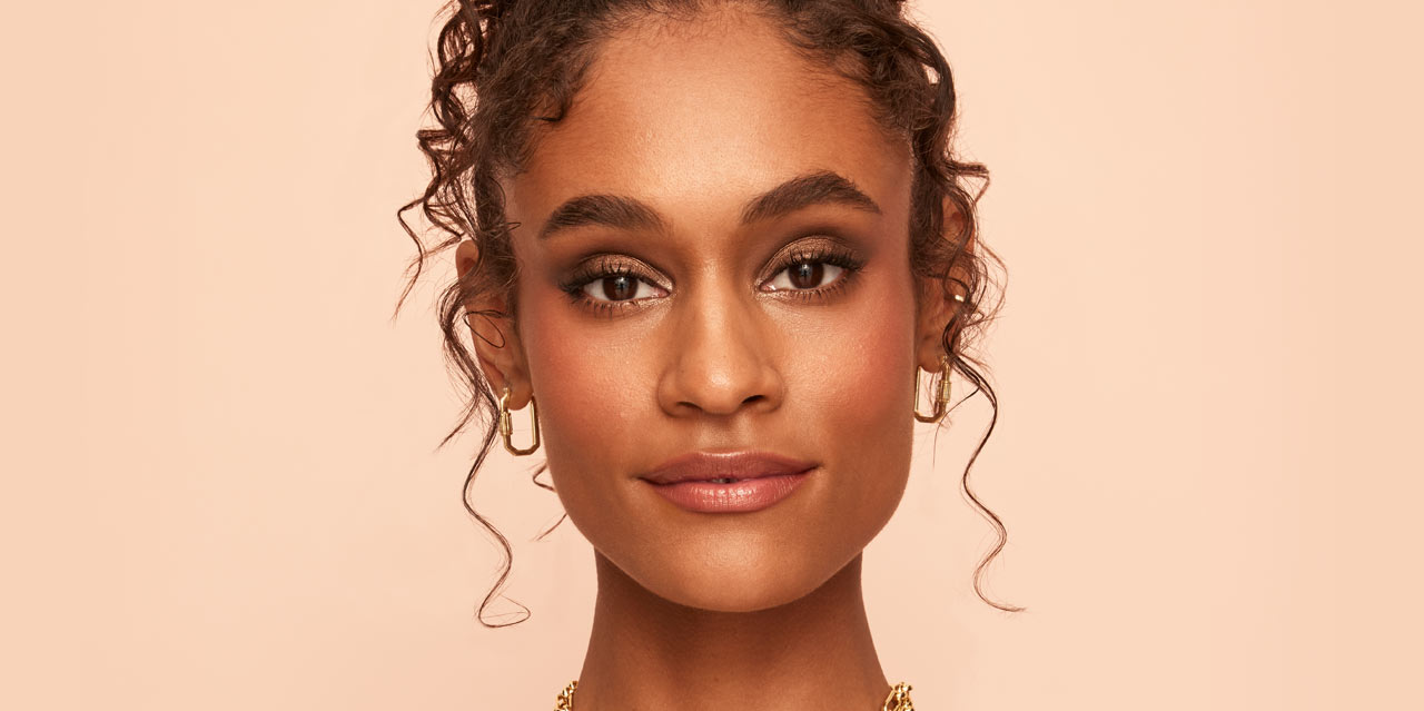 Warm brown smokey eye look and bronzed skin worn on a model with dark skin tone